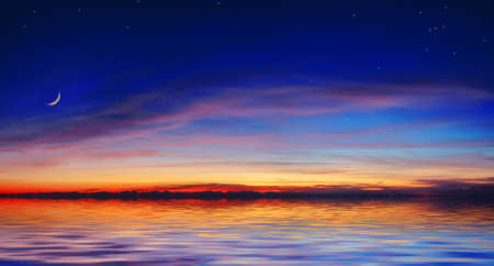 The quiet sea on a background of a beautiful sunset with the moon and starsの写真素材