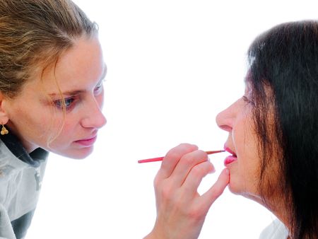Young the stylist prepares lady for photographing on a white backgroundの写真素材