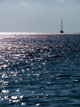 Patches of light on the sea on horizon it is visible a sailing vesselの写真素材