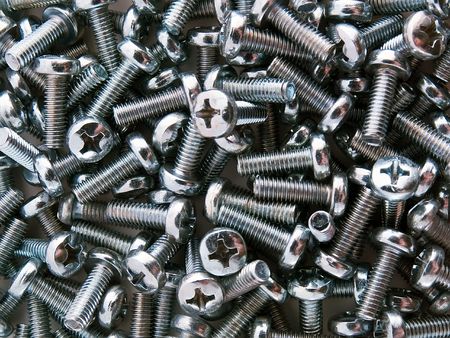It is a lot of screws scattered on a white table or a texture from screws.の写真素材