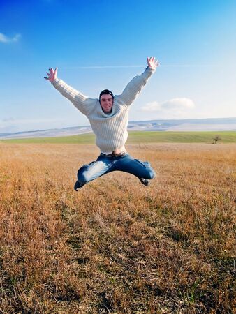 The guy jumps on a background of mountains and plantsの写真素材