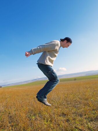 The guy jumps on a background of mountains and plantsの写真素材