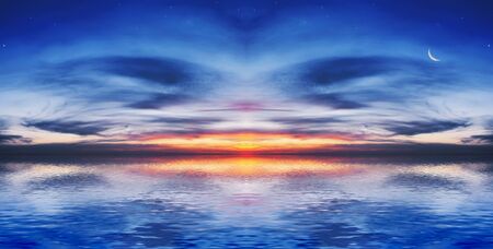 The quiet sea on a background of a beautiful sunset with the moon and starsの写真素材