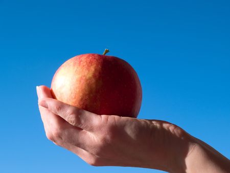 The artist holds an apple on a hand and paints it in red colorの写真素材