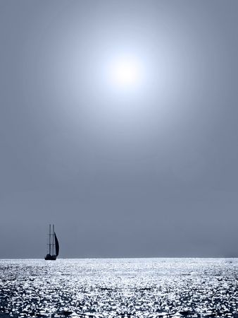 Patches of light on the sea on horizon it is visible a sailing vessel の写真素材