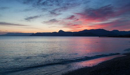sunset with beautiful clouds reflected in the calm water of the oceanの写真素材