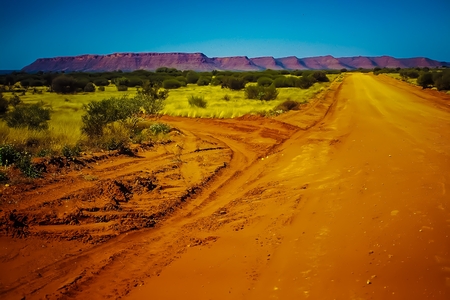 A Desert Road and Red Rock Range in the Background - Mereenie Loop - Watarrka National Park - Australiaの写真素材