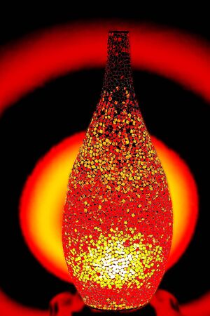 Creative lamp made by small pieces of red glass lights up the roomの写真素材