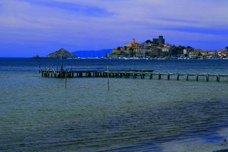 Village by seaside with a castle in the background - Talamone - Tuscany - Italyのeditorial素材