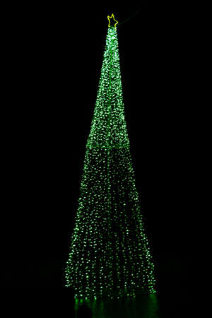 Christmas tree decorated with bright lights and a christmas star on the top in a dark night