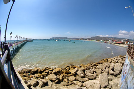 Fishing boats in the harbor beyond a stone jetty in Puerto Lopez, Ecuadorの写真素材