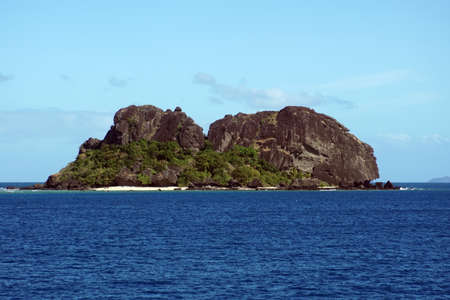 Clear blue water around a beach on a rugged island in Fijiの写真素材