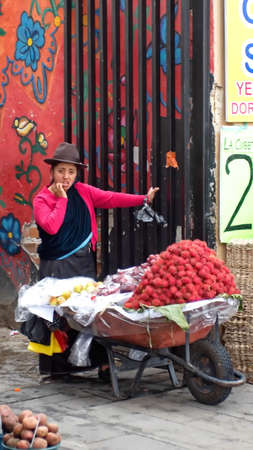 Vendor selling fruit from a wheelbarrow on the sidewalk in Cuenca, Ecuadorのeditorial素材