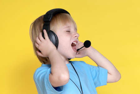 The emotional kid in ear-phones on a yellow background の写真素材