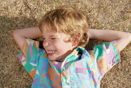 The little boy laying on a dry grassの写真素材