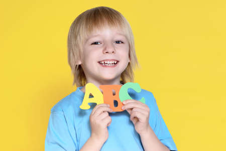 The small schoolboy with letters on a yellow backgroundの写真素材