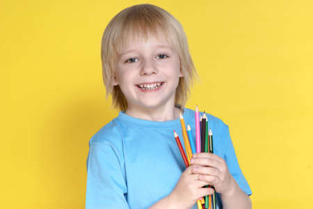 The small schoolboy with pencils on a yellow backgroundの写真素材