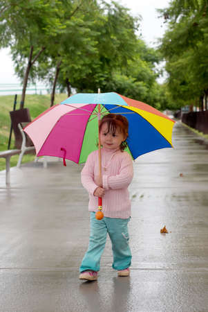 The little girl with an umbrella standing under a rain の写真素材