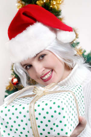 Beautiful christmas woman in santa hat holding giftの写真素材