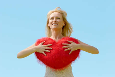 The beautiful woman with heart in hands against the skyの写真素材