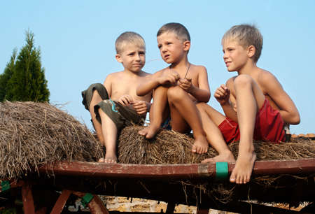 boys sitting on a hay bale on sky background の写真素材