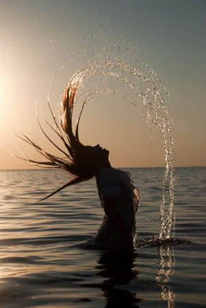 Motion freeze on a girl splashing the sea water with her hairの写真素材