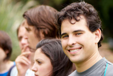Portrait young happy teenage boy at the park with friends