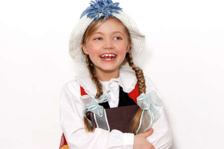 The nice schoolgirl in a hat with the book on a light backgroundの写真素材