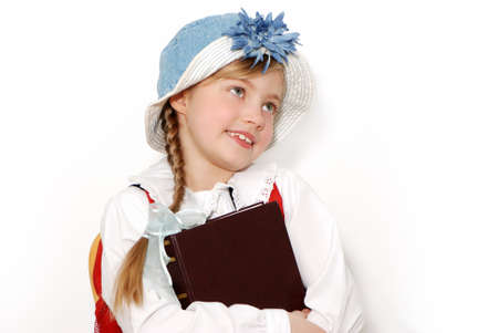 The nice schoolgirl in a hat with the book on a light backgroundの写真素材
