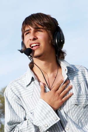 Singing teenage boy in headphones against the nature