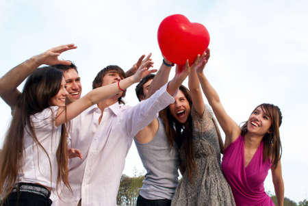 Group of young guys and girls with a sphere in the form of heartの写真素材