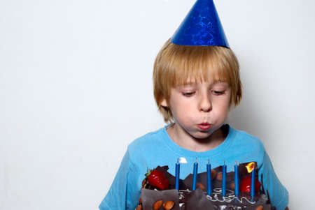 boy blowing on the candles placed in the cakeの写真素材