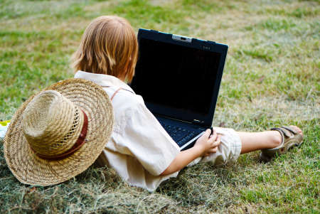 The boy reading notebook sitting in a haystackの写真素材