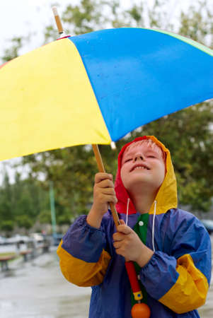 The boy with an umbrella standing under a rainの写真素材