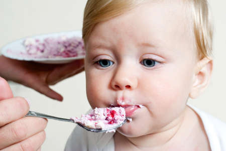 Little boy eating baby food with spoonの写真素材