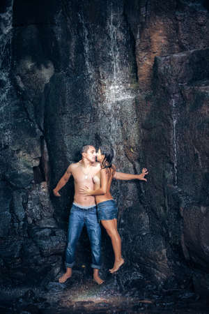 Couple hugging and kissing under waterfallの写真素材