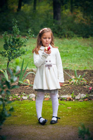 little girl is eating apple outdoorの写真素材