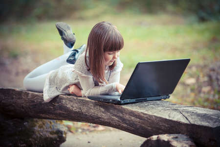 Child in autumn park with laptopの写真素材