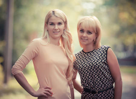 two smiling attractive young women outdoorsの写真素材