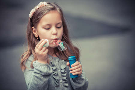 Portrait of funny lovely little girl blowing soap bubbleの写真素材