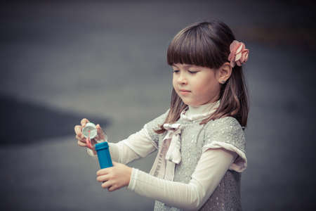 Portrait of funny lovely little girl blowing soap bubbleの写真素材