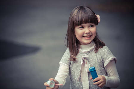 Portrait of funny lovely little girl blowing soap bubbleの写真素材