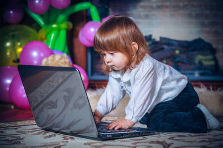 little baby playing with laptop on a carpet