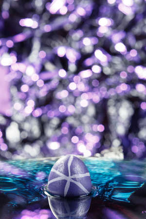 Purple easter egg in blue waterの写真素材