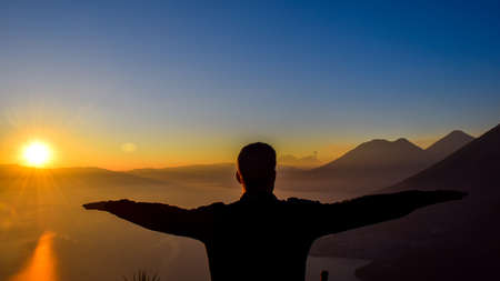 Dawn views of Lake Atitlan and hiker doing shapes from the heights of Indian Nose pointviewの写真素材