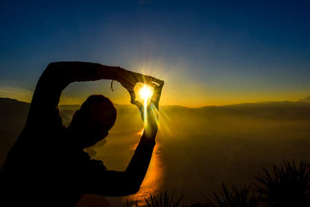 Dawn views of Lake Atitlan and hiker doing shapes from the heights of Indian Nose pointviewの写真素材