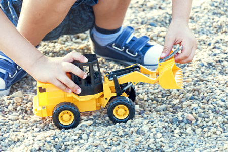 Kid plays with yellow toy excavatorの写真素材