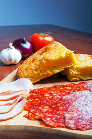 Cornbread with cheese, vegetables and meat on cutting board