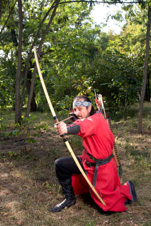 Man in medieval dress aims a bow.の写真素材