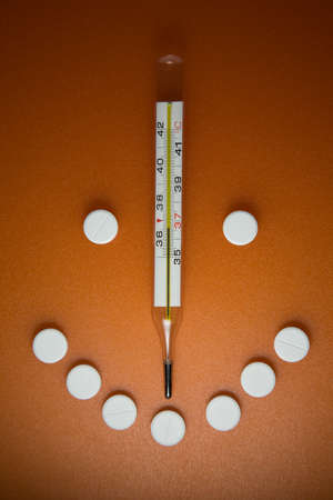 Medical thermometer and pills arranged in a smiley face with a smile.の写真素材